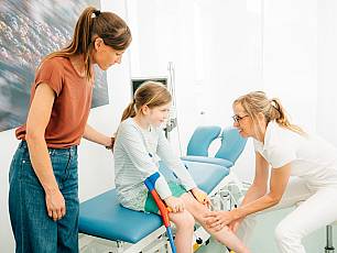 Fr. Dr. Endele untersucht Bein eines Kindes mit Krücken