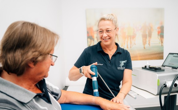 Patient bekommt Stoßwellentherapie am Arm